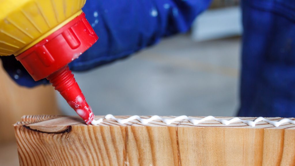 Carpenter at work crafting using glue in his workshop on cut wood. Craftsman working glueing.